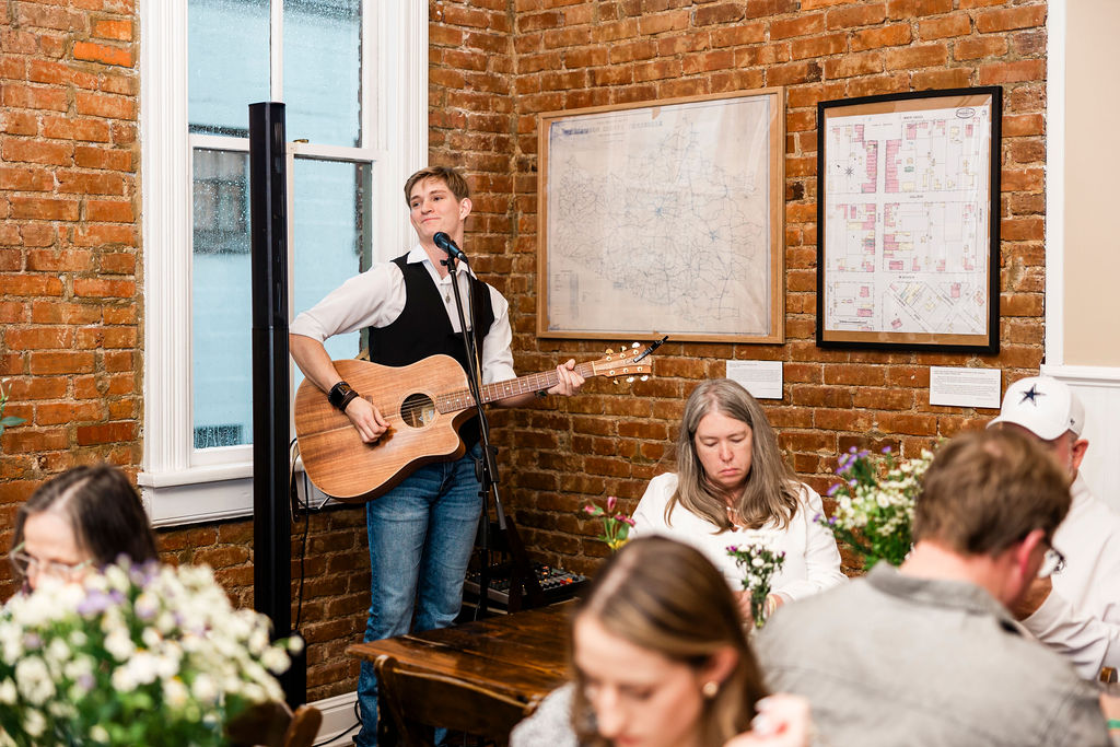 Solo acoustic performer against an exposed brick wall