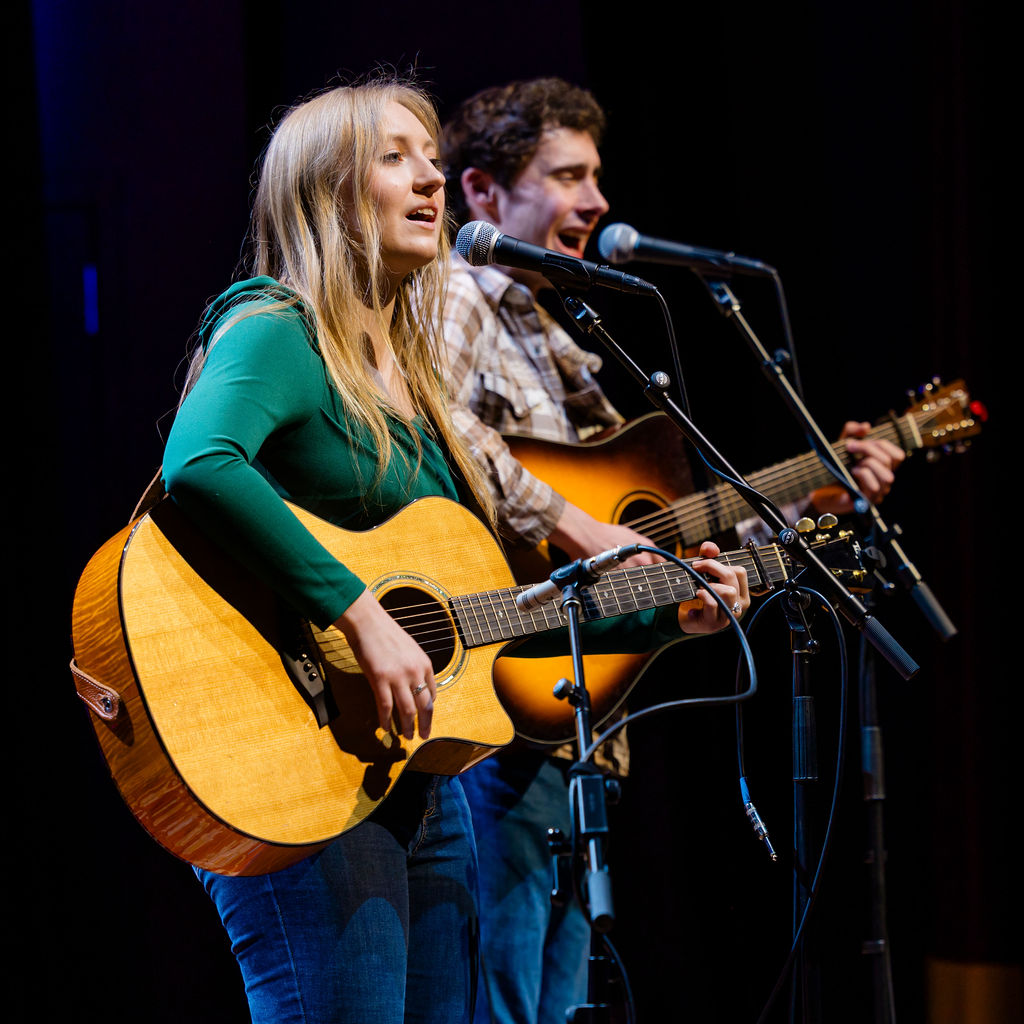 Acoustic duo performing on stage under warm light