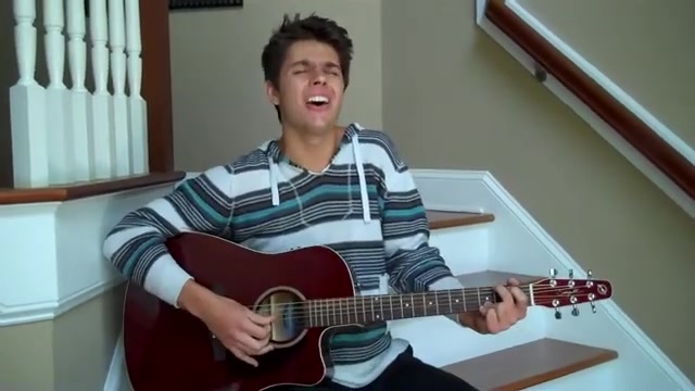 Cole in a striped hoodie, singing Broken and Lost with his acoustic guitar