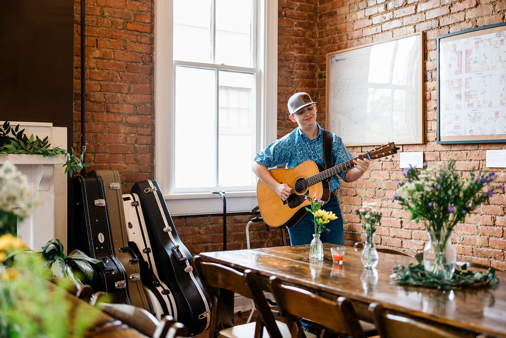 Young guitarist playing in a room with guitar cases stacked nearby