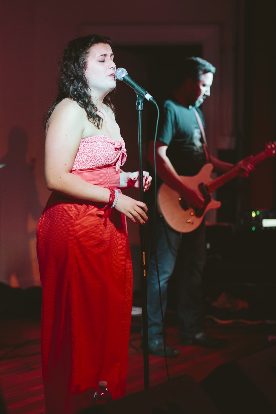 Vocalist singing on stage in a red dress under warm stage lighting